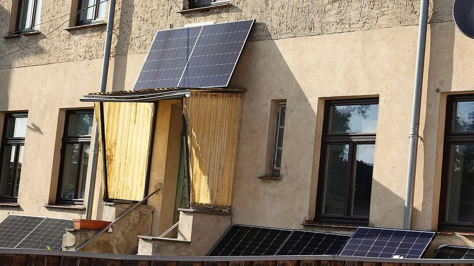 Gevel van een woning met zonnepanelen aan het balkon en in de voortuin