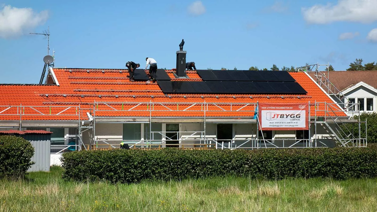 Installateurs leggen zonnepanelen op het dak van een woning met steigers